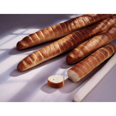 Baguettes fraîchement cuites sur une surface blanche, avec une tranche de pain et un bâtonnet de pâte visibles.