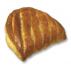 Pâtisserie cuite au four, de couleur brun doré, probablement un chausson aux pommes, avec un bord cannelé et un dessus rayé.