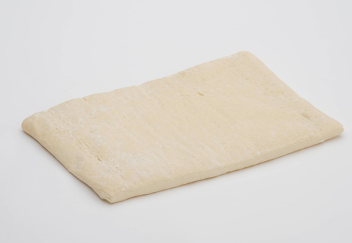 Rectangle de pâte crue, de couleur beige clair, posé sur une surface blanche.