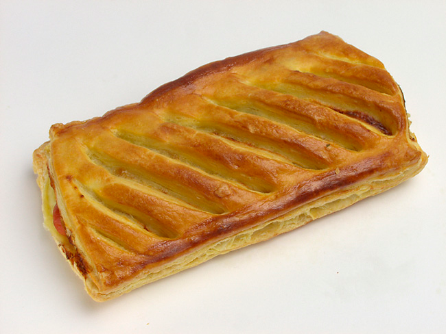 Pâtisserie dorée à décor en treillis diagonal, posée sur une surface blanche.