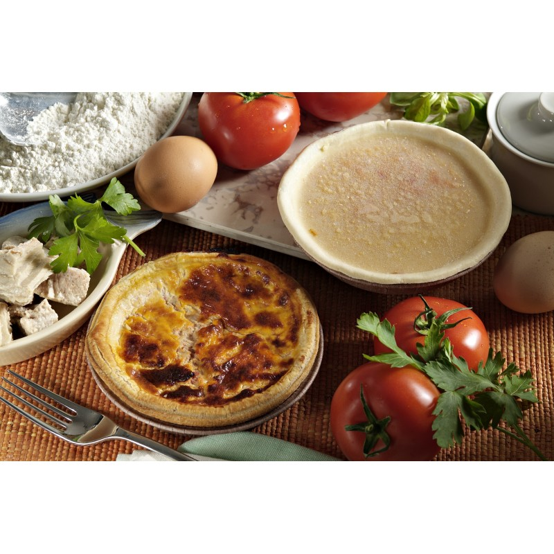 Une quiche avec des ingrédients comme des tomates, des œufs et de la farine sur une table.