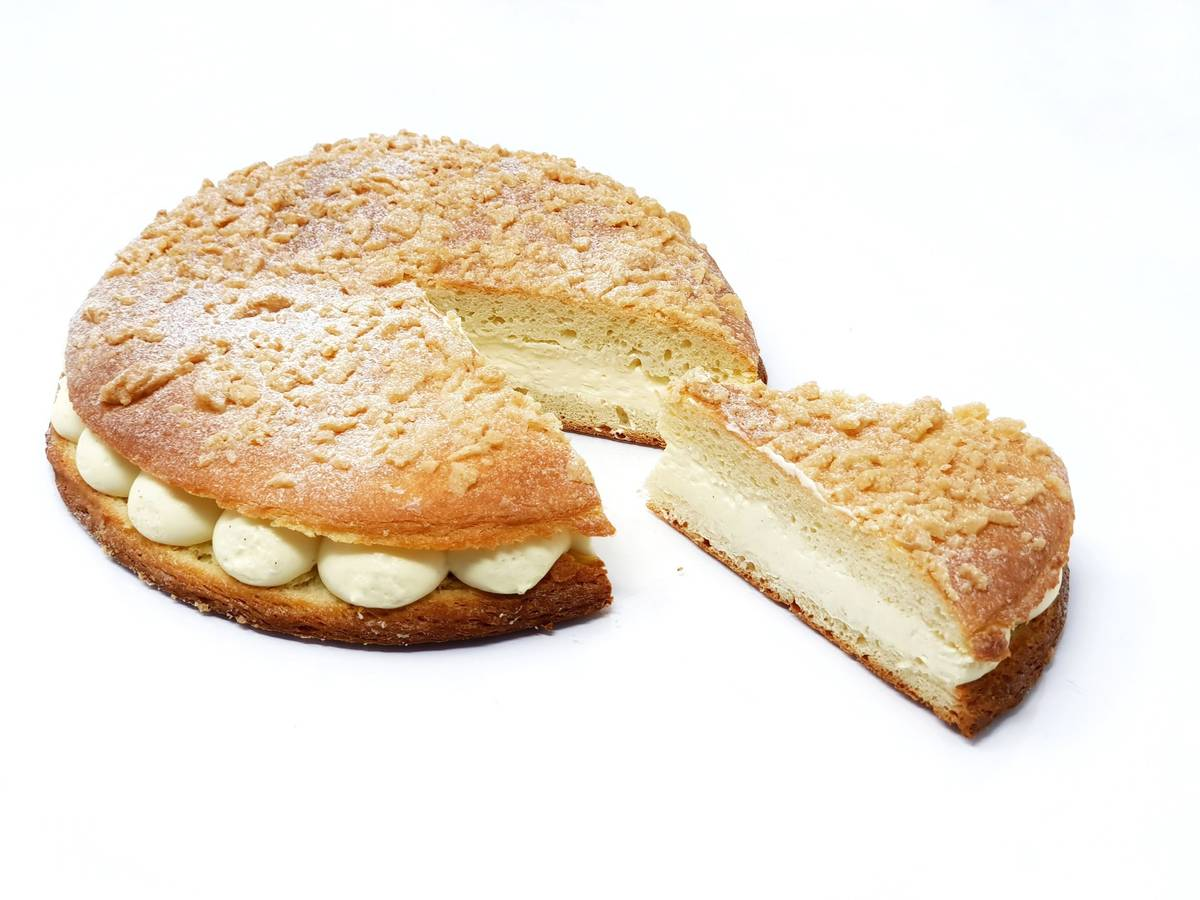 Gâteau coupé en parts, fourré à la crème et recouvert de miettes, sur fond blanc.