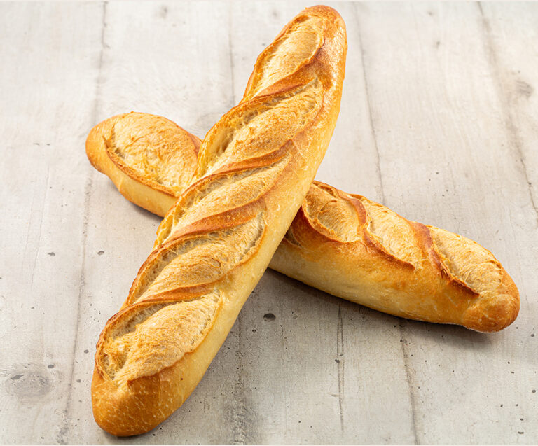 Deux baguettes brun doré sur une surface en bois clair.