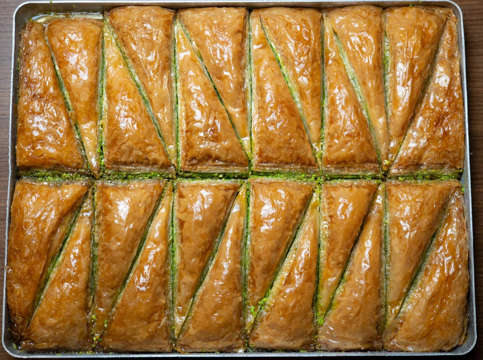 Pâtisseries baklava sur un plateau, dorées et coupées en triangles.