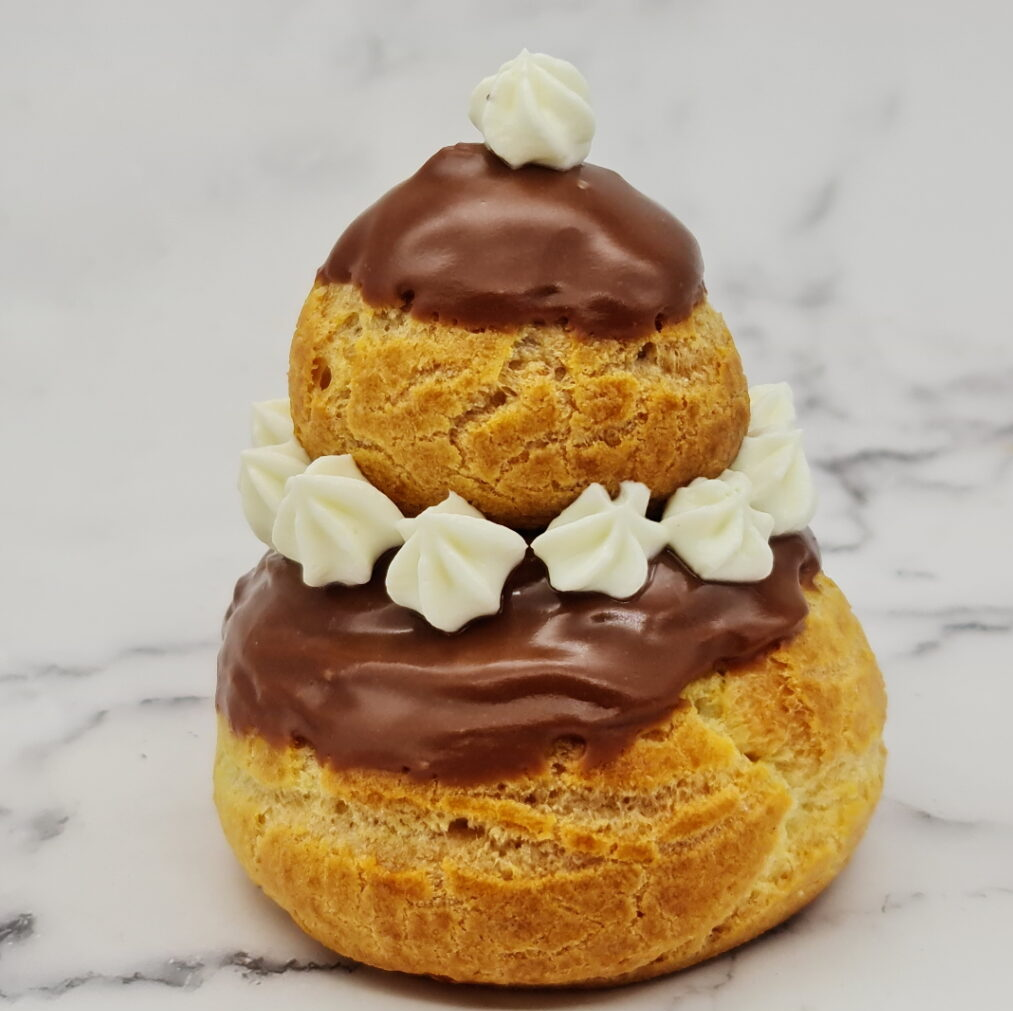 Pâtisserie à choux à deux étages, garnie de ganache au chocolat et de quenelles de crème fouettée.