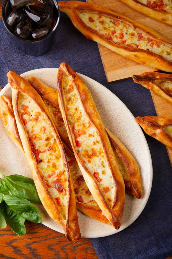 Pains pide garnis de fromage et de tomates sur une assiette et une planche