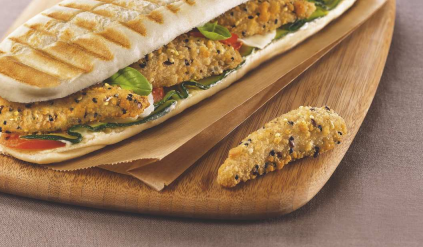 Panini au poulet servi sur une planche en bois avec une lanière de poulet.