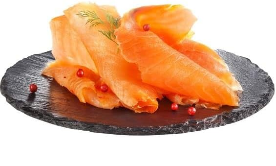 Tranches de saumon fumé sur une assiette foncée à la texture travaillée, garnies d'aneth et de baies roses.