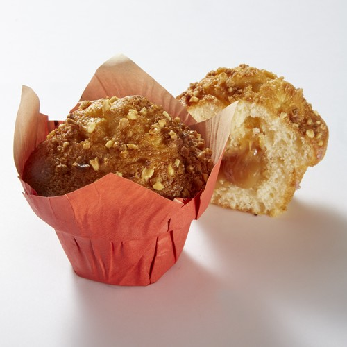 Deux muffins, un entier et l'autre coupé en deux, dans des caissettes en papier rouge, garnis de noix.