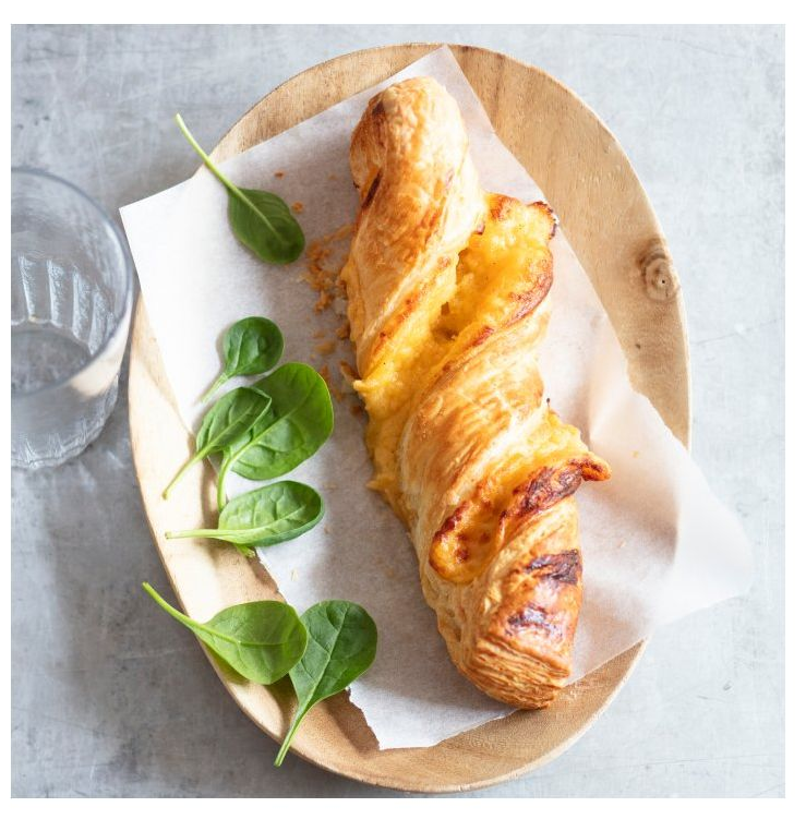 Pâtisserie torsadée au fromage, feuilles d'épinards et verre d'eau sur une assiette en bois.