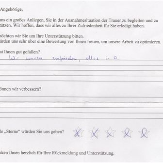 Ein handschriftliches Feedback-Formular zur Trauerfeier. Wörter wie „zufrieden“ und „Sterne“ sind sichtbar, mit drei Sternen markiert.