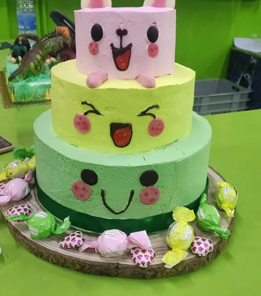 Un pastel de tres niveles con un conejito rosa encima.