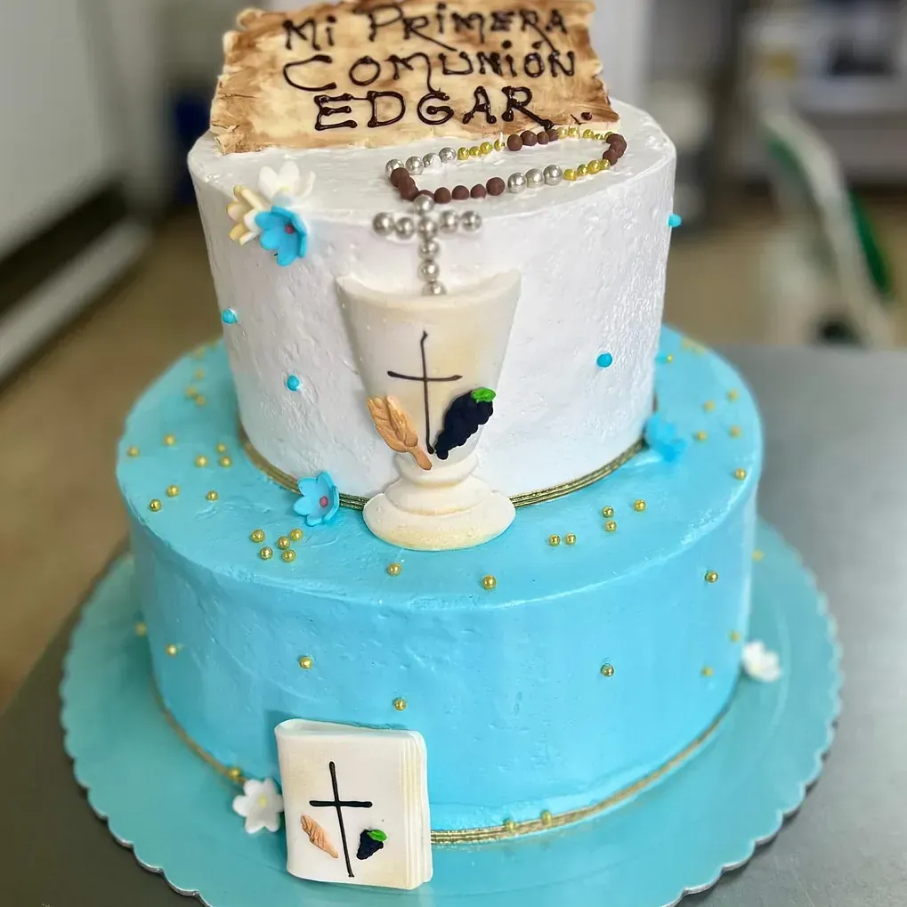 Un pastel azul y blanco con un cáliz y una cruz sobre él.