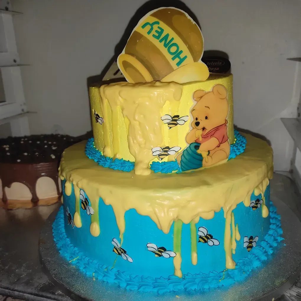 Un pastel con Winnie the Pooh y miel encima.