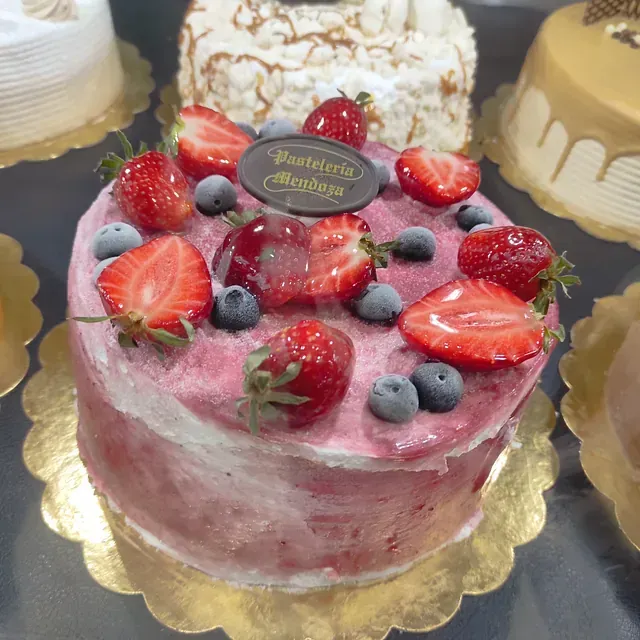 Una tarta con fresas y arándanos tiene un cartel que dice pasteleria