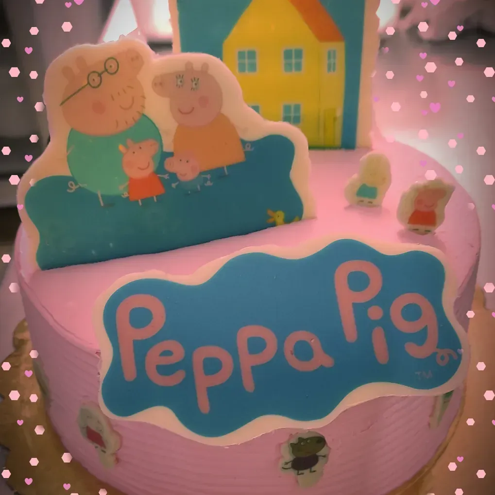 Un pastel rosa con un cartel azul que dice Peppa Pig.