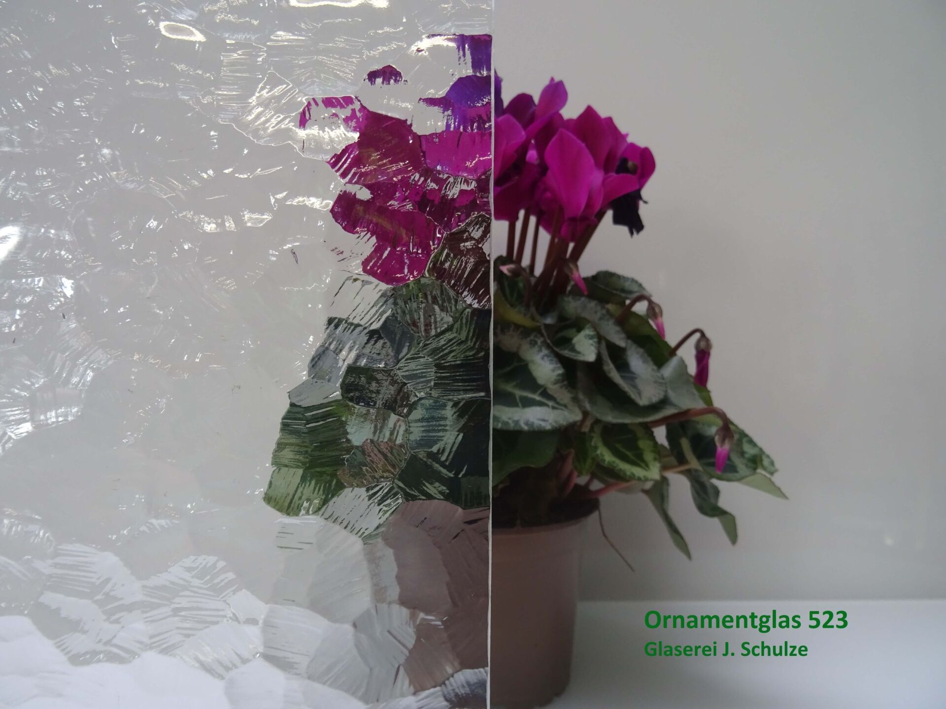 Milchglas vor Blumentopf mit pinker Pflanze