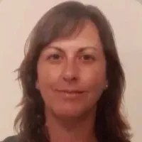 Retrato de una persona con cabello castaño hasta los hombros sobre un fondo claro liso.