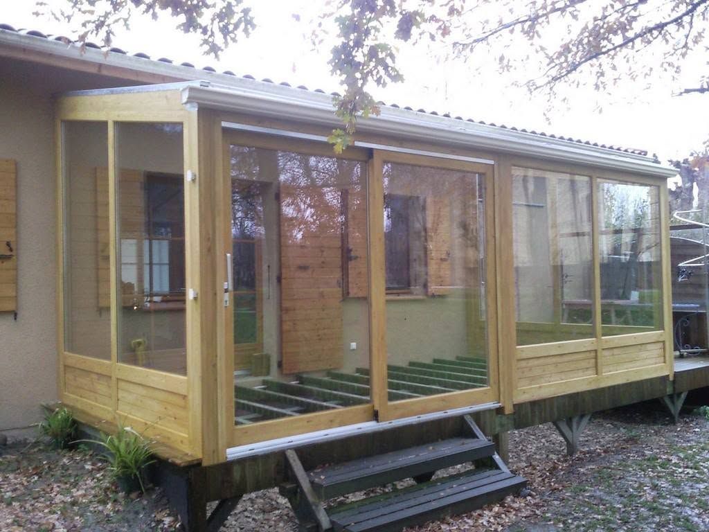 Extension de véranda en bois avec de grandes fenêtres et des marches à l’extérieur d’une maison