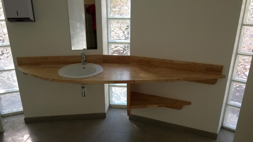 Plan de toilette mural en bois avec vasque ronde, dans une pièce moderne dotée de fenêtres en briques de verre