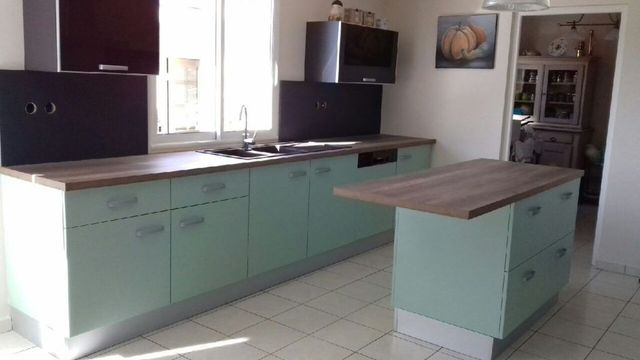 Cuisine moderne avec des placards vert menthe, des plans de travail en bois et un îlot assorti