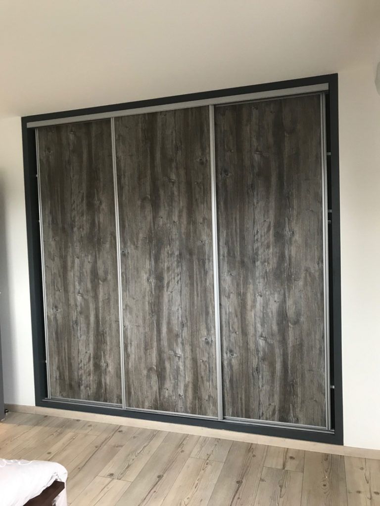 Portes de placard coulissantes de style grange, dans une pièce avec un parquet clair et des boiseries foncées.