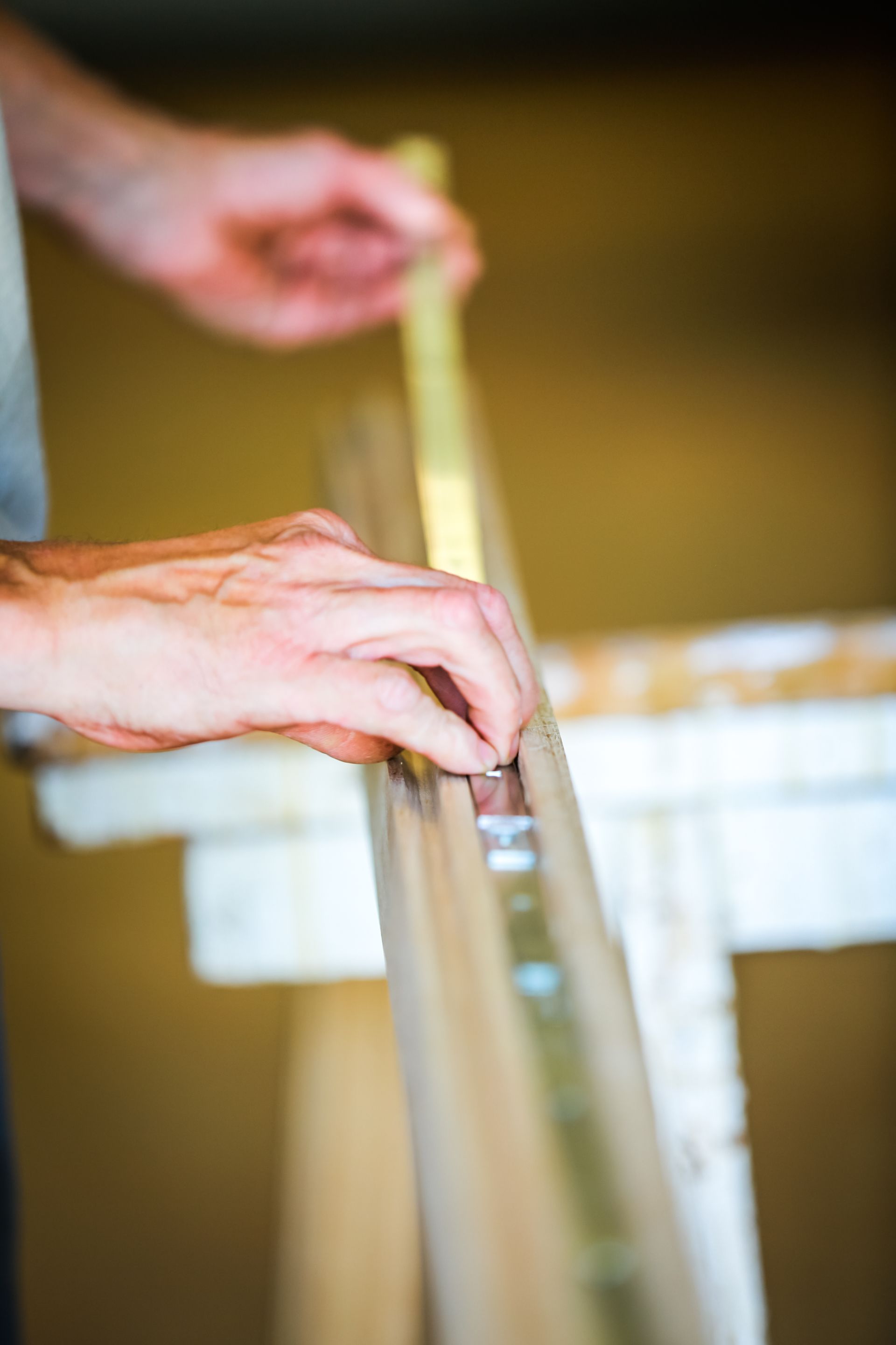 Des mains qui guident une planche en bois dans une boîte en carton pendant l’emballage