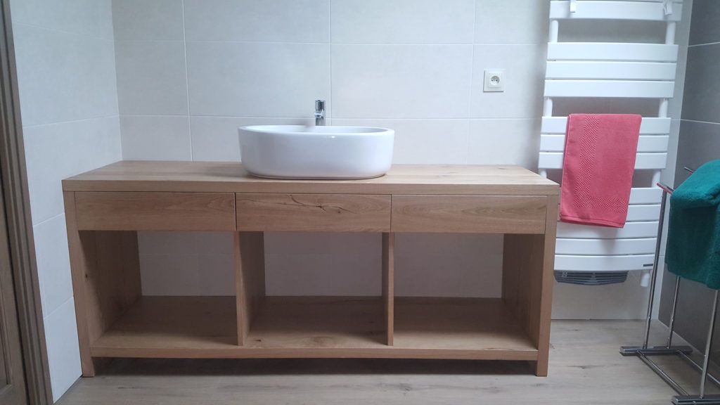 Meuble-lavabo moderne avec piètement en bois, vasque blanche et serviette rose sur un sèche-serviettes radiateur