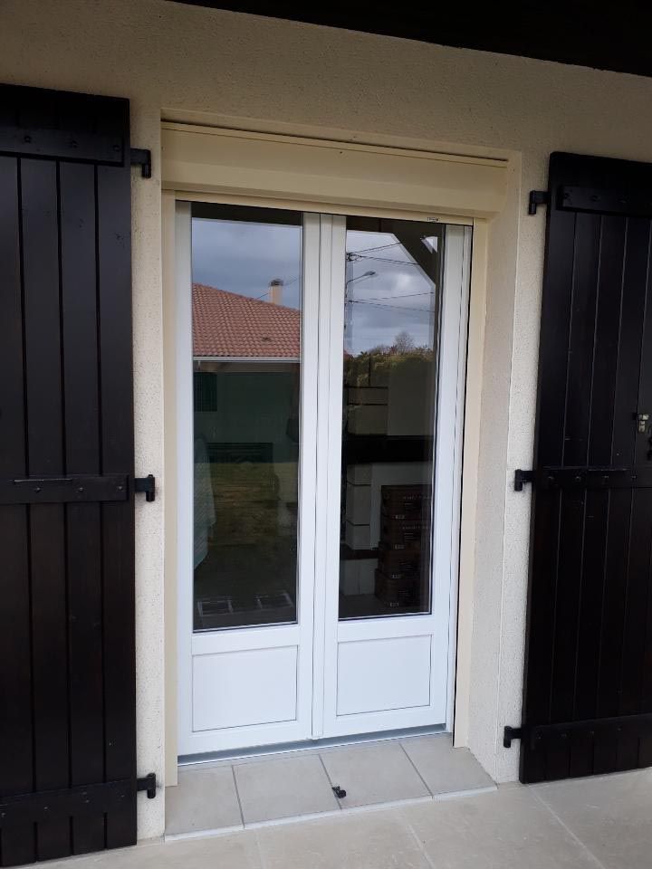 Portes-fenêtres blanches à double battant, avec des volets noirs de chaque côté, vues de l’extérieur.