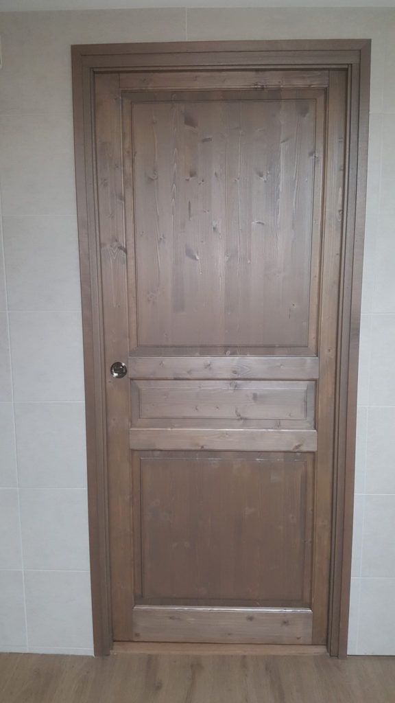 Porte intérieure en bois avec une poignée sombre, intégrée dans un mur carrelé.