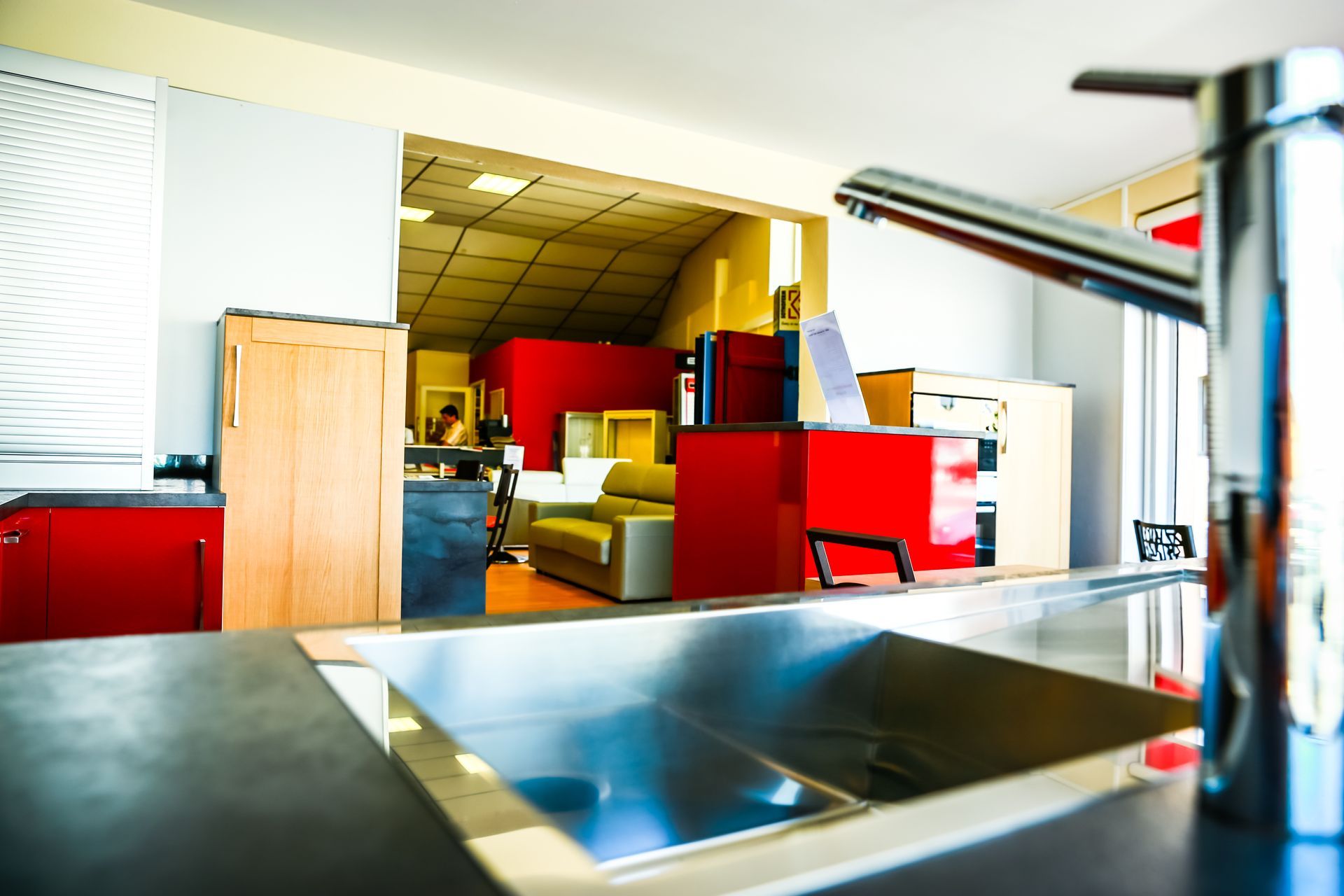 Cuisine moderne avec évier, placards rouges et salle à manger lumineuse éclairée par le plafond