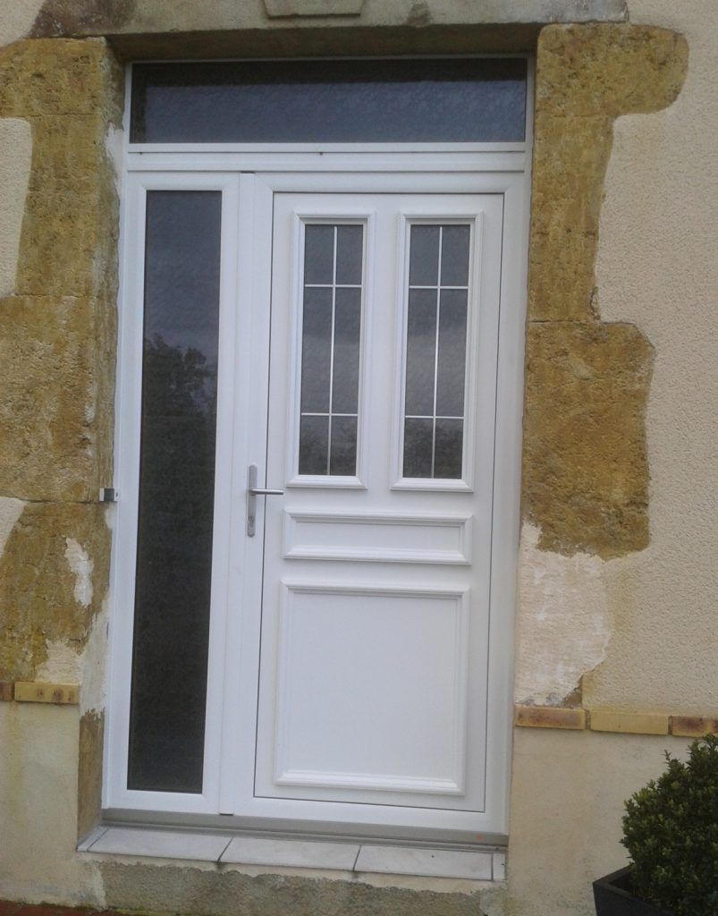 Porte d’entrée blanche avec panneaux vitrés et fenêtre latérale, dans un mur extérieur en pierre