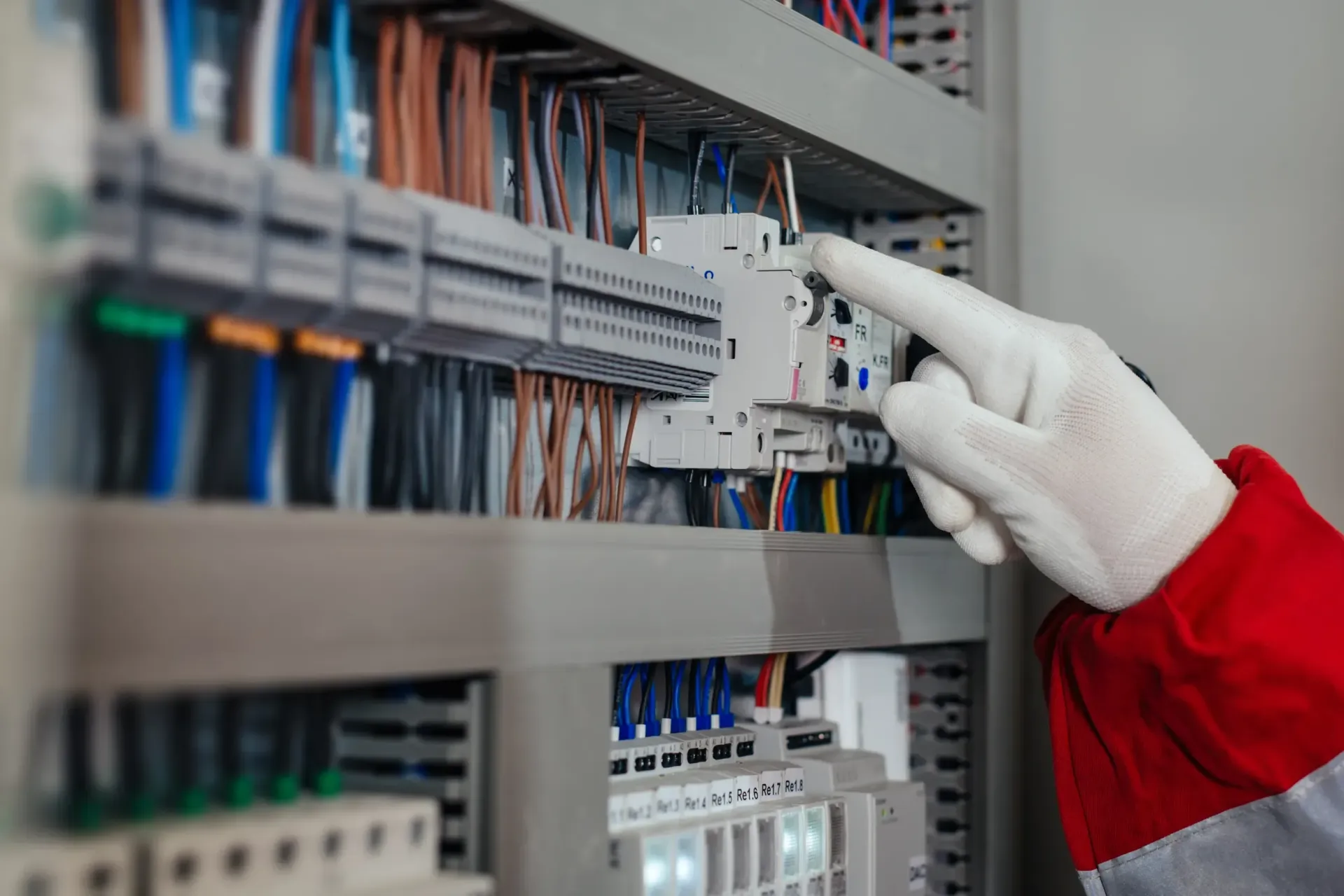 Una mano en un guante blanco apunta a un panel de control con cables.