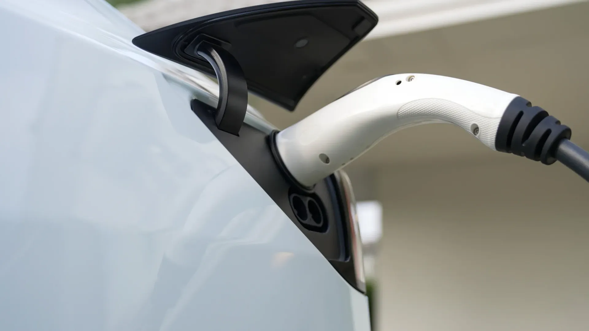 Persona instalando cables eléctricos en una caja de enchufe blanca. Cables rojos y verdes visibles.