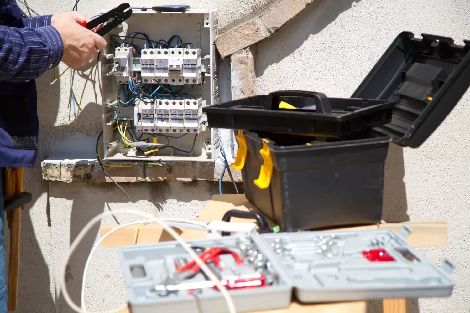 Persona trabajando en una caja eléctrica con herramientas.