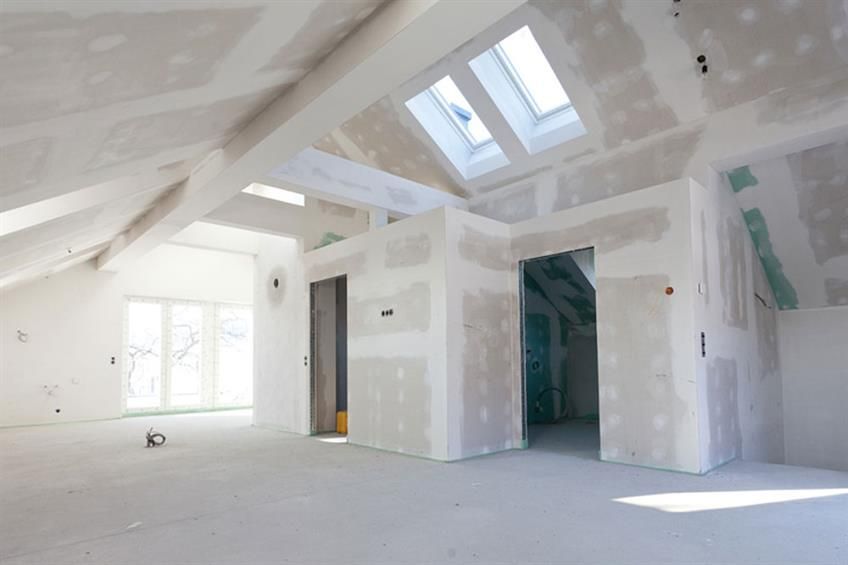 Ein leerer Raum mit Gipskartonwänden und einem Oberlicht in der Decke.
