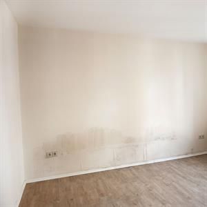 Ein leerer Raum mit einer weißen Wand und Holzboden.