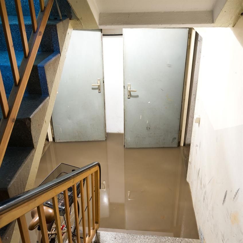 Eine überflutete Treppe mit einem Holzgeländer und einigen Türen.