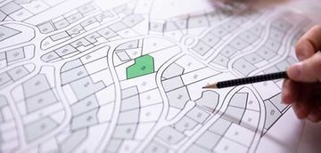 Una persona señala un área verde en un mapa con un lápiz.