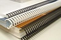 Tres libros encuadernados en espiral están apilados uno encima del otro sobre una mesa.