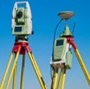 Dos estaciones totales sobre trípodes contra un cielo azul.