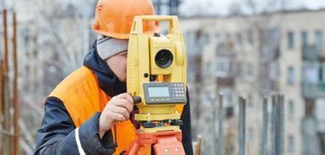 Un trabajador de la construcción está utilizando un teodolito en un sitio de construcción.