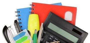 Una calculadora está encima de una pila de material de oficina.