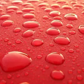Un primer plano de gotas de agua sobre una superficie roja.