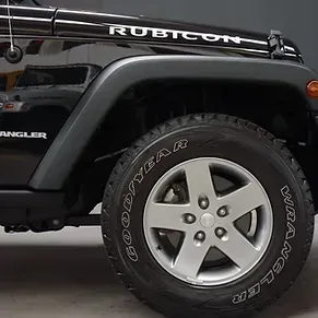 Un Jeep Wrangler Rubicon negro está estacionado en un garaje.