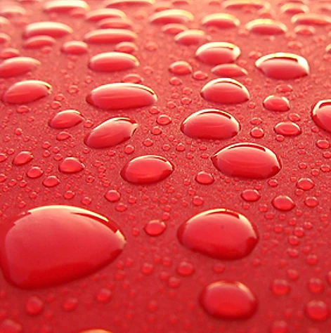 Un primer plano de gotas de agua sobre una superficie roja.