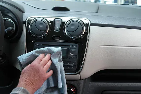 Una persona está limpiando el tablero de un automóvil con un paño.