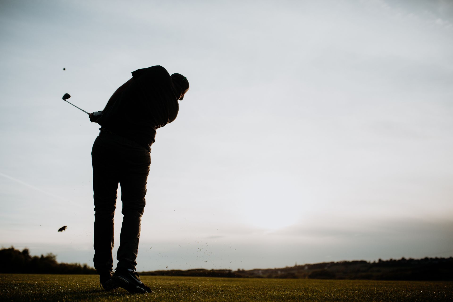 Silhouette eines Golfers mitten im Schwung auf einem Golfplatz bei Sonnenuntergang