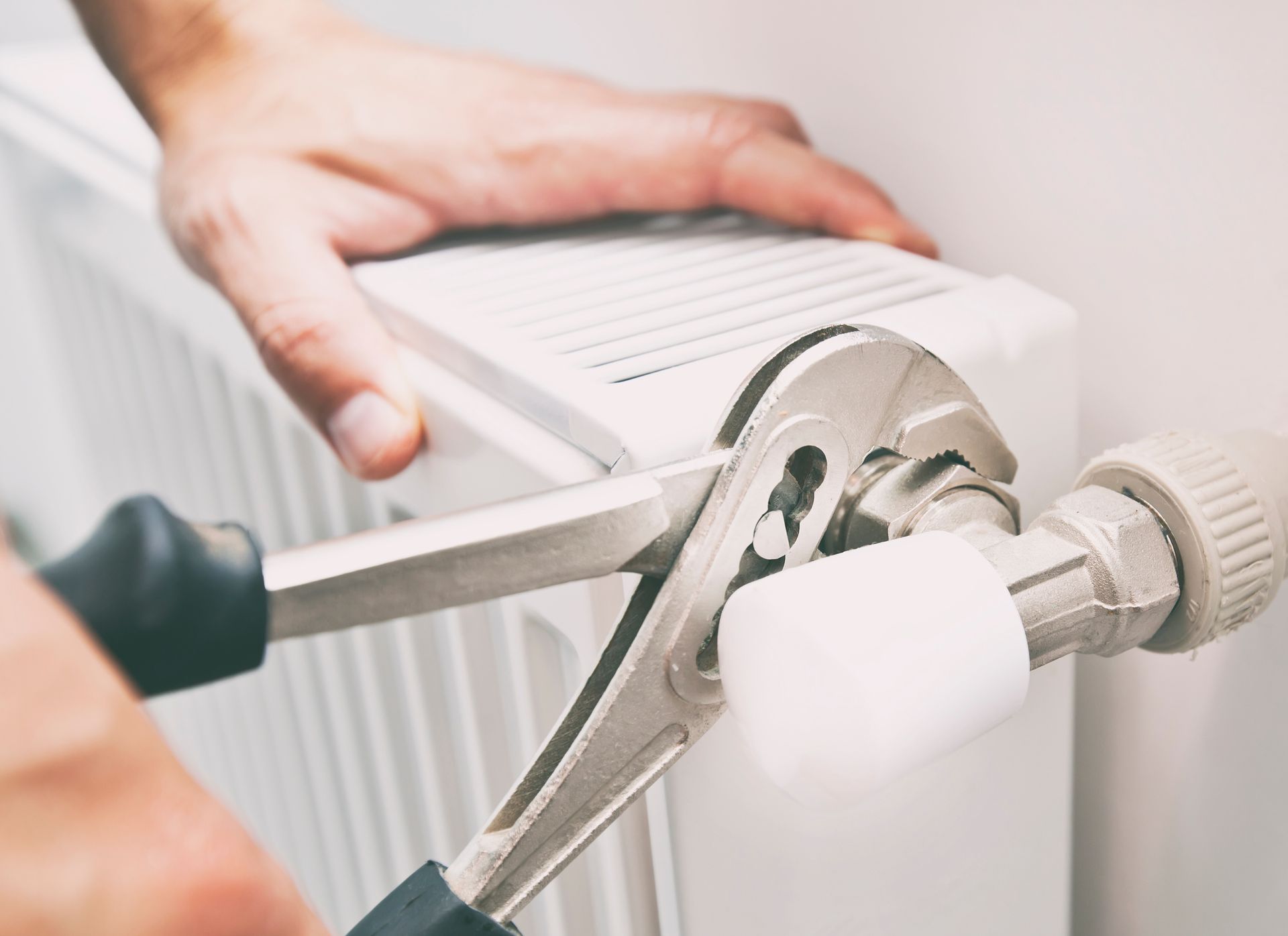 Un professionnel qui est en train de resserrer le robinet du radiateur. 