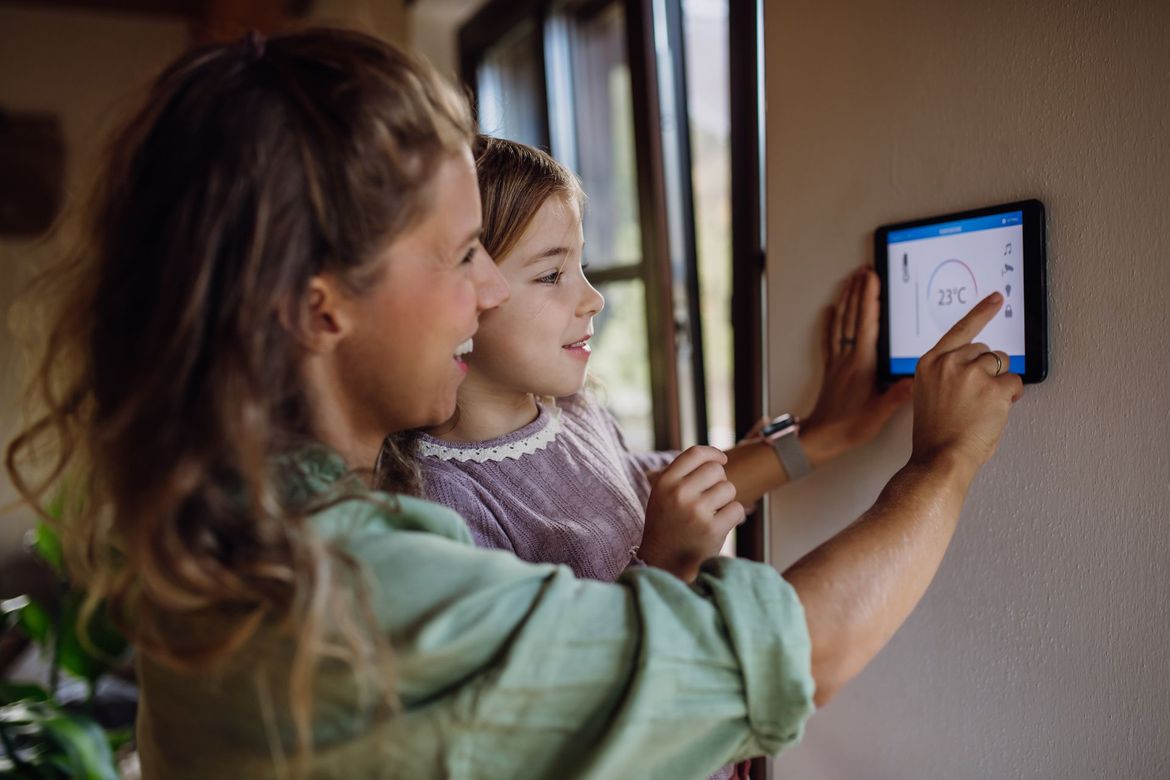Une mère et sa fille règlent le thermostat.